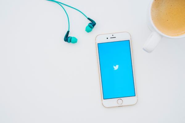 コーヒーとイヤフォンとTwitterのロゴが映るスマートフォン