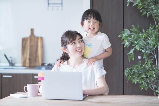 パソコンで在宅ワーク中のママと子どもの様子