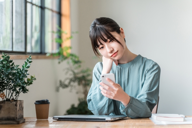 スマホを見て悩む女性